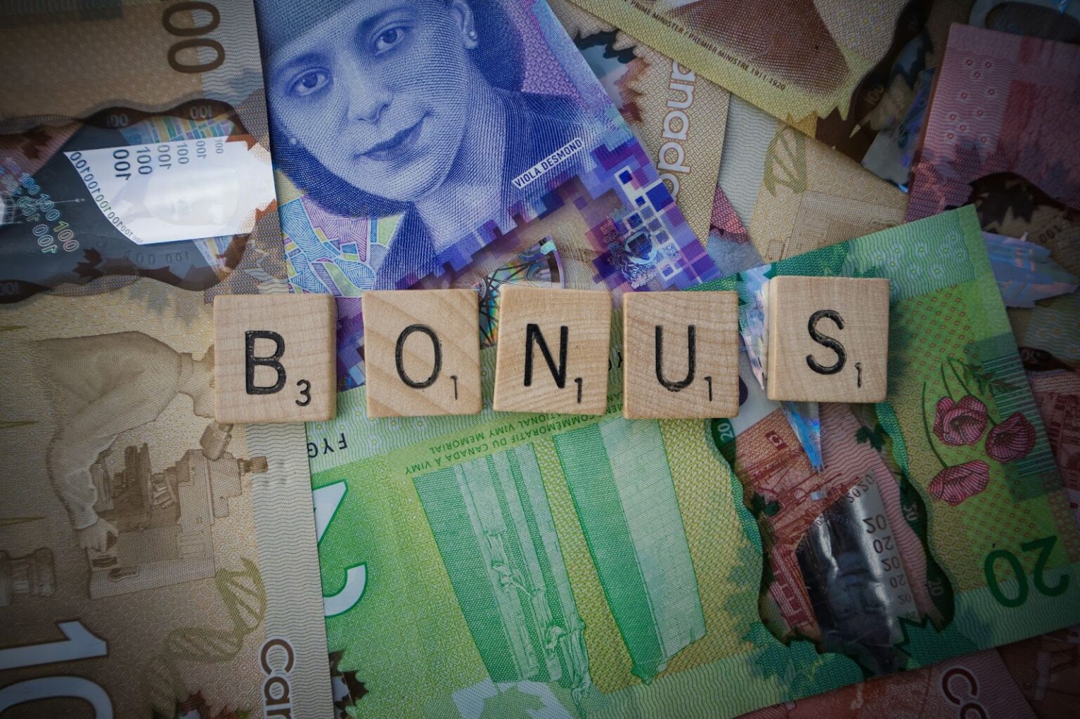 The word "Bonus" spelled out in Scrabble tiles on a collage background